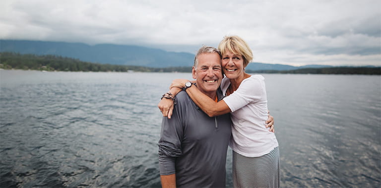 A couple stands in front of a lake